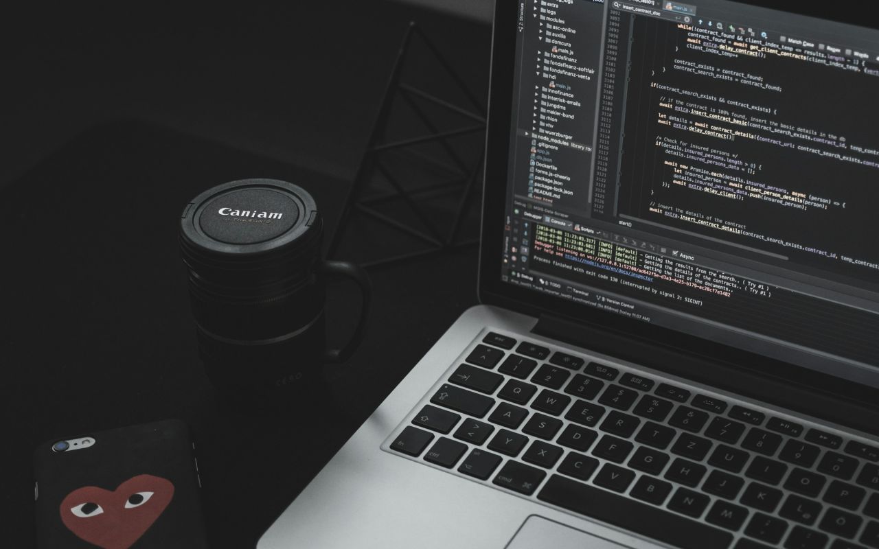 An open laptop next to a black mug