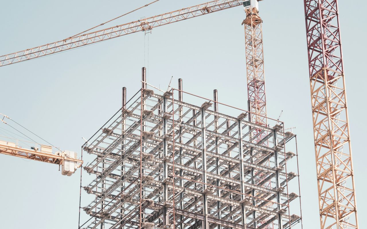 A steel building frame next to a tower crane