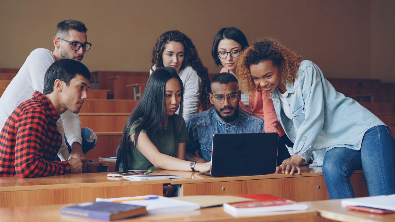 A group of students gathered around a laptop