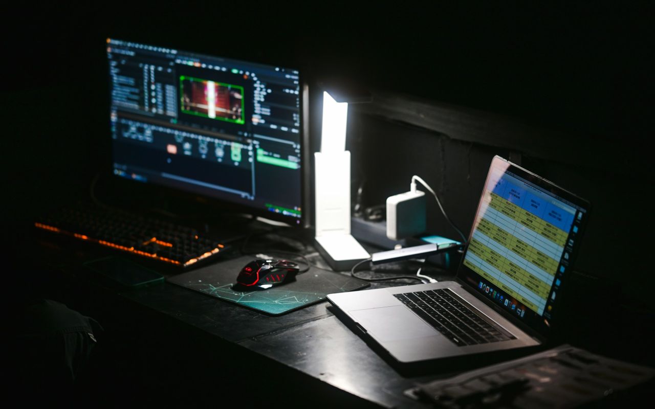 A laptop and a monitor on a dark desk